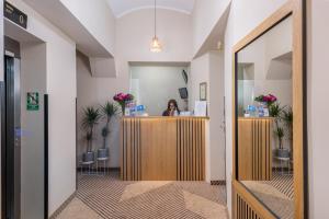 a woman sitting at a counter in a room with plants at Hotel Yarden by Artery Hotels in Krakow