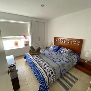 a bedroom with a bed with a blue and white comforter at Departamentos Amoblados Frente al Mar Manta -PROINKASA in Manta