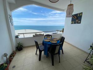 een tafel en stoelen op een balkon met uitzicht op de oceaan bij Departamentos Amoblados Frente al Mar Manta -PROINKASA in Manta