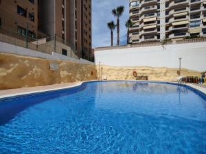 ein großer blauer Pool in der Mitte der Gebäude in der Unterkunft ESTRELLA honey apartment in Cala de Finestrat