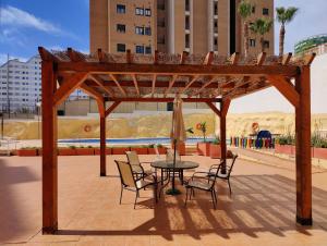 eine hölzerne Pergola mit einem Tisch und Stühlen in der Unterkunft ESTRELLA honey apartment in Cala de Finestrat