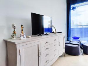 eine weiße Kommode mit einem Fernseher darüber in der Unterkunft ESTRELLA honey apartment in Cala de Finestrat