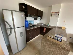 a kitchen with a white refrigerator and brown cabinets at Departamentos Amoblados Frente al Mar Manta -PROINKASA in Manta