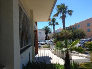 a building with a gate and a parking lot with palm trees at Maison de la plage in Valras-Plage