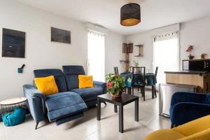 una sala de estar con sofás azules y almohadas amarillas. en Appart avec 3 chambres au pied du TRAM avec internet !, en Eysines