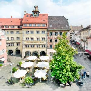 een groot gebouw met witte parasols ervoor bij Romantik Hotel Barbarossa in Konstanz