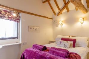 a bedroom with a bed with purple sheets and a window at Garden Cottage in Diss
