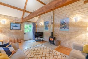 a living room with a brick wall and a fireplace at Stable Cottage, Freams Farm in Painswick
