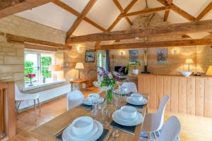 a dining room with a wooden table and white chairs at Stable Cottage, Freams Farm in Painswick