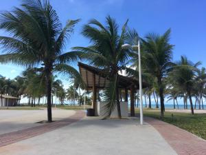a pavilion with palm trees next to a beach at Chalé em frente à Praia in Salvador
