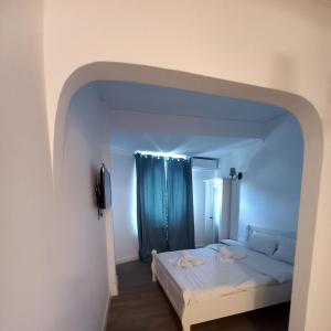 a bedroom with a white bed with a blue curtain at Adrys Boutique Villa in Constanţa