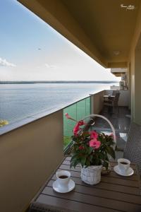 a table with two cups and flowers on a balcony at SARA Moonlight Residence in Mamaia