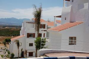 a white building with palm trees in front of it at Apartement cabo in Tétouan +16 photos