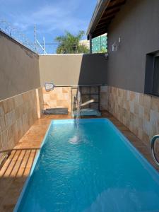 una piscina con una fuente frente a una casa en Casa Thermas Olimpia I - 150 metros do Thermas dos Laranjais, en Olímpia