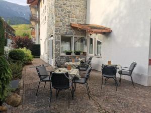 un patio con mesa y sillas y un edificio en Hotel Garni Sottobosco, en Dimaro