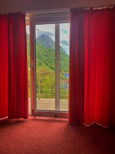 a window with red curtains and a view of a mountain at Hotel International in Băile Herculane +1 photo