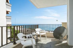 a balcony with white chairs and a view of the ocean at Hauzify I Apartament Nautilus in Salou +13 photos