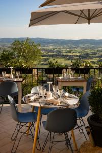 una mesa y sillas en un patio con sombrilla en Hotel Posta Panoramic Assisi, en Asís