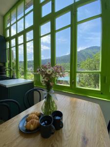 a table with a vase of flowers and a plate of food at Polifonia Inn Borjomi in Borjomi