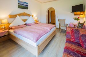 a bedroom with a large bed and a tv at Hotel-Pension-Ostler in Bad Wiessee