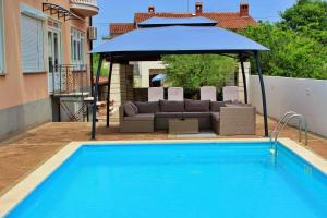 una piscina con sofá y sombrilla azul en Apartments Kimm, en Poreč