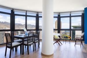 a dining room with a table and chairs and windows at Home2Book Stunning Santa Cruz City Views in Santa Cruz de Tenerife
