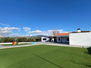 a large green yard with a building and a playground at El cortijo del abuelo pepe in Alhendín