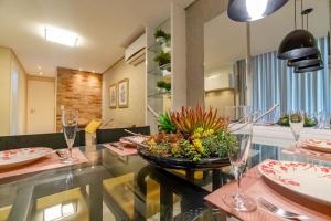 a dining room with a table with plates and glasses at Varandas do Atlântico, Condo Frente Mar com Piscina Climatizada - 3 quartos 6 pessoas in Bombinhas