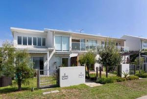 a large white house with a fence at Silver Beach Penthouse in Kurnell