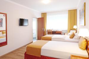 a hotel room with two beds and a television at Hotel Mennicken in Würselen