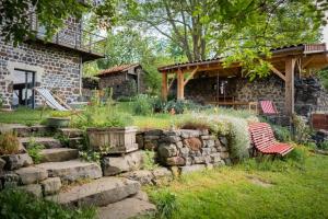 a garden with a stone wall and two chairs in front of a house at Les Balcons de la Terrasse in Arsac-en-Velay