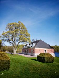 ein großes rotes Backsteinhaus mit einem Baum im Hof in der Unterkunft The Norrmans Castle in Genarp