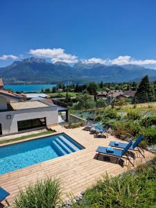 a villa with a swimming pool and mountains in the background at Appartement Thiou in Sévrier