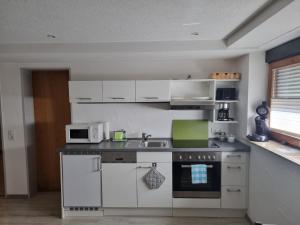 a kitchen with white cabinets and a sink and a microwave at Ferienwohnung Alina in Rust