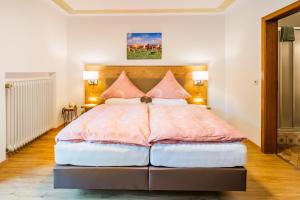 a bedroom with a large bed with pink pillows at Hotel-Pension-Ostler in Bad Wiessee