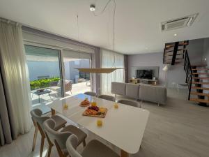 een eetkamer en een woonkamer met een witte tafel en stoelen bij Zadar Premium Apartments in Kožino