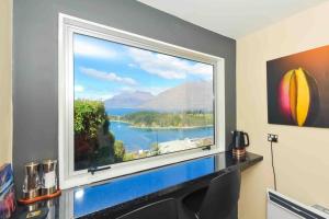 a large window with a view of a lake at Lovely Apartment- Amazing Lake & Mountain Views in Queenstown