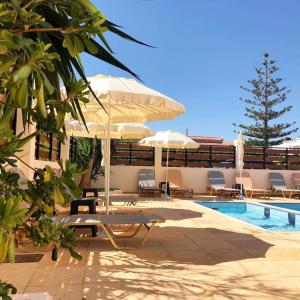 a swimming pool with chairs and umbrellas next to a swimming pool at Nirevel Apartments in Gouves