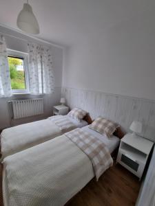 two beds in a white room with two tables at Przystanek Podgórze in Duszniki Zdrój