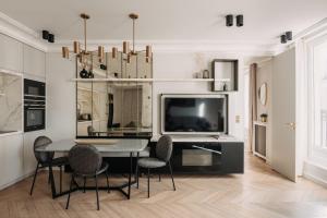 a dining room with a table and chairs and a tv at HIGHSTAY - Luxury Serviced Apartments - Louvre-Rivoli in Paris