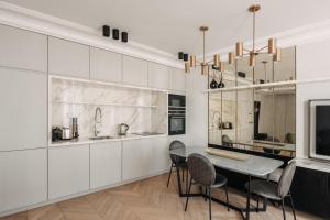 パリにあるHIGHSTAY - Luxury Serviced Apartments - Louvre-Rivoliの白いキャビネット、テーブルと椅子付きのキッチンが備わります。