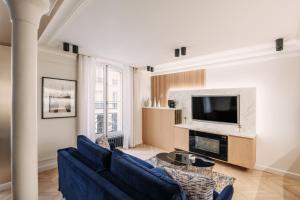 a living room with a blue couch and a tv at HIGHSTAY - Luxury Serviced Apartments - Louvre-Rivoli in Paris