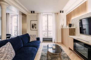 a living room with a blue couch and a tv at HIGHSTAY - Luxury Serviced Apartments - Louvre-Rivoli in Paris +34 photos