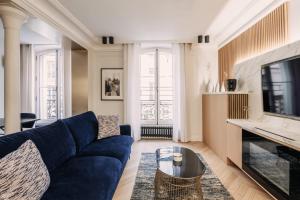 a living room with a blue couch and a tv at HIGHSTAY - Luxury Serviced Apartments - Louvre-Rivoli Area in Paris