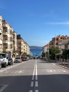 una calle vacía con coches aparcados a un lado de la carretera en Trébol junto a playa Silgar, en Sanxenxo