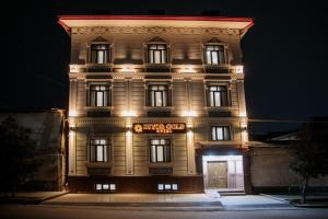um edifício alto com luzes acesas à noite em Diyor Gold Hotel em Samarkand
