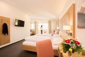 ein Hotelzimmer mit weißen Möbeln und eine Frau, die durchs Fenster geht in der Unterkunft Panorama Hotel Flora in Villanders
