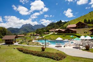 a resort with a pool and mountains in the background at Fazenda Suica Le Canton in Teresópolis