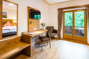 Habitación de hotel con escritorio, cama y ventana en Hotel-Pension-Ostler, en Bad Wiessee