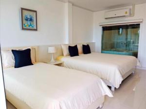 2 Betten in einem Zimmer mit weißer Bettwäsche und blauen Kissen in der Unterkunft Koh Larn Riviera in Ko Larn